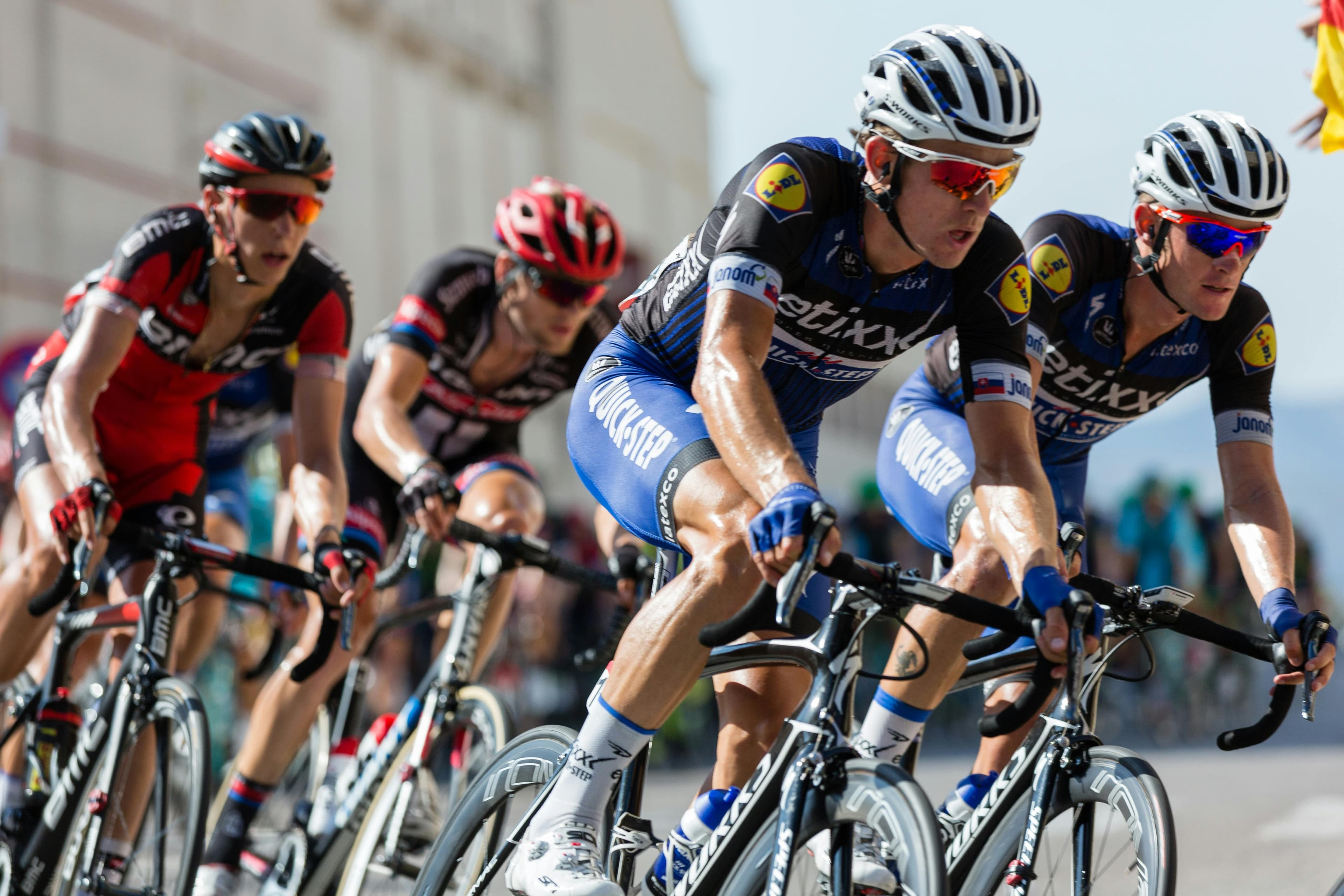 The peloton stretching out on a climb — the grupetto forming at the back.
